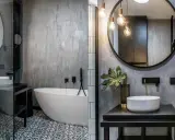 Nowoczesna łazienka w stylu loft z wolnostojącą wanną, umywalką nablatową i betonową ścianą.
