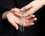 Mani delicate tengono tre scintillanti bracciali tennis, un classico intramontabile la cui storia affonda le radici nel mondo dello sport.