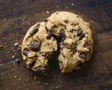 Un cookie aux pépites de chocolat, brisé en deux, révèle sa texture moelleuse. La meilleure recette de cookies pour un goûter gourmand.