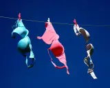 Tre reggiseni colorati (blu, rosa, bianco) stesi ad asciugare al sole. Forse non portare il reggiseno fa crescere il seno, ma l'aria aperta li fa asciugare bene!