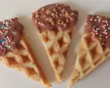 Drei dreieckige Waffeln, mit Schokolade überzogen und bunt bestreut, warten darauf, von Kindern beim Waffeln dekorieren vernascht zu werden.