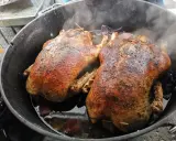 Zwei goldbraune Enten garen im Dutch Oven. Dampf steigt auf, während die Enten im eigenen Saft schmoren.
