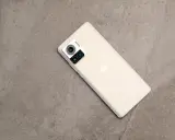 Jasny telefon Motorola edge 30 ultra z potrójnym aparatem na szarym, kamiennym tle.