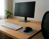 Bureau en bois avec écran, clavier, souris et tapis. Un fauteuil de bureau noir est visible. L'ergonomie travail sur écran est essentielle pour le confort.