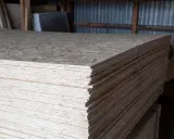 Stos płyt OSB, grubość 18 mm, gotowych do użycia w budowie.