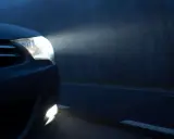 El alumbrado de posición de un coche ilumina la niebla en una carretera oscura.