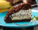 Ein Stück saftiger Maulwurfkuchen vom Blech mit Bananen und Schokostückchen in der Creme, garniert mit Sahne und Minze.