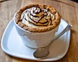 Un délicieux dessert dans une tasse en cookies, garni de crème fouettée et de sauce au chocolat.