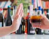 Dłoń odrzuca szklankę z alkoholem, symbolizując początek leczenia alkoholizmu.
