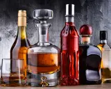 Karafka z koniakiem i inne butelki z brandy na drewnianym blacie.