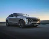 Cadillac Lyriq, un SUV eléctrico que representa el futuro de las marcas americanas de coches, avanza por una carretera al atardecer.