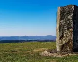 Steinerner Gedenkstein auf der Wasserkuppe mit Blick über Hügel und Täler.