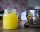 En burk med hemgjord lemon curd står bredvid en metallskål.