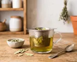 Infusion de feuille de séné, danger potentiel pour la santé. Une tasse de thé fumant avec des feuilles dans un infuseur, à côté d'un bol de feuilles séchées et d'une cuillère.