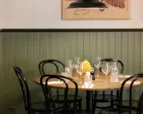 Ett runt bord med dukning för middag, med vinglas och en gul dekoration. En inbjudande atmosfär på la bottega del gusto.