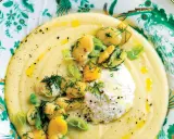 Macco di fave fresche cremoso, guarnito con fave intere, ricotta fresca e aneto, servito su un piatto decorato.