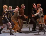 Scène de théâtre tendue. Des hommes se disputent, leurs gestes évoquent une lutte. La scène rappelle la conjugaison du verbe "aboyer" dans un moment de tension.