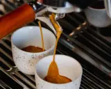 Frisch gebrühter Espresso fließt in zwei Tassen. Hoffentlich schmeckt er nicht zu sauer.