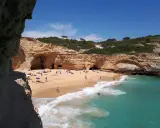Sonniger Strand an der Algarve, ein echter Geheimtipp mit Felsformationen und türkisfarbenem Wasser. Menschen entspannen sich am Sandstrand.