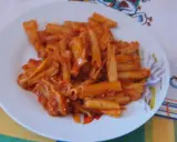 Penne rigate w bogatym sosie pomidorowym, podane na białym talerzu. Pyszny obiad gotowy!