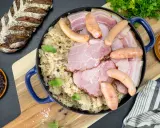 Un plat généreux de choucroute de Noël, garni de saucisses, jambon et lard, accompagné d'une miche de pain rustique.