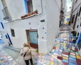 Callejuela de **Chelva pueblo azul**, con escalones de colores vibrantes y casas blancas adornadas con detalles azules.