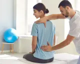 Fizjoterapeuta bada plecy pacjentki, sprawdzając potencjalne objawy przewianych nerek.