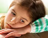Smutna dziewczynka, 9 latek nie radzi sobie z emocjami, opiera głowę na ramieniu.