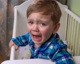 Niño de 10 años llorando en su cuna, se comporta como bebé.