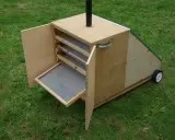 Un sechoir solaire diy en bois, avec des étagères et une porte ouverte sur un tamis. Idéal pour sécher des herbes ou des fruits au soleil.