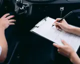 Kobieta wypełnia formularz podczas rejestracji samochodu przez dealera.