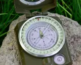 Kompas na kamieniu i trawie. To narzędzie jest kluczowe w bushcraft, co to znaczy? To sztuka przetrwania w dziczy.