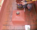 Persona aplica pintura para impermeabilizar terraza. Cubeta de Mariseal y desagüe en el centro.