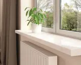 Jasny parapet wewnętrzny z marmurowym wzorem i zieloną rośliną w białej doniczce. Inspiracja, jak dobrać kolor parapetu wewnętrznego.