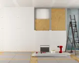 Chantier de pose de plaques de plâtre, avec échelle, perceuse et matériaux. Estimation du prix placo m2.