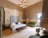Ett lyxigt sovrum med en stor säng, grön soffa och en imponerande eldstad. Perfekt hotell inredning inspiration för ett elegant hem.