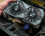 Main d'homme tenant une carte graphique double ventilateur. Pour savoir si une carte graphique est morte, vérifiez les artefacts visuels ou l'absence de signal.