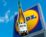 Botella de vino blanco Coto de Ibedo con etiqueta colorida, frente a un cartel de Lidl.