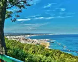 Vista panoramica della Riviera Romagnola con mare azzurro, spiagge affollate e una città costiera. Ideale per il turismo.