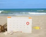 Kalendarz na plaży z zaznaczonym 14. dniem. Czas na urlop bezpłatny i relaks nad morzem.