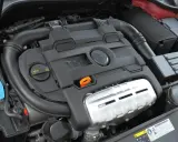 Silnik 1.4 TSI z widocznym logo VW. Czarna pokrywa silnika z napisem TSI i pomarańczową pętlą do sprawdzania oleju.
