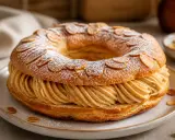 Un Paris-Brest, rond et généreux, garni de crème pralinée, saupoudré de sucre glace et d'amandes effilées. Une invitation à la gourmandise.