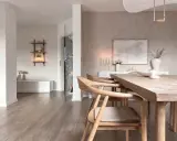 Interni in stile wabi sabi con tavolo in legno grezzo, sedie in legno chiaro e decorazioni minimaliste.