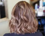 Piękne, falowane brązowe włosy z subtelnymi blond refleksami, które dodają im głębi i blasku.