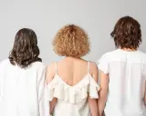 Trzy kobiety z tyłu. Jedna ma falowane, ciemne włosy, druga krótkie, kręcone blond włosy w stylu boho, trzecia falowane, brązowe włosy.