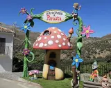 Bienvenido a Parauta, inicio de la ruta del bosque encantado. Un duende saluda desde un arco con flores y un hongo mágico.