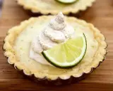 En liten key lime pie med en virvel av gräddig topping och en limeklyfta.