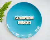 Niebieski talerz z literami tworzącymi napis "WEIGHT LOSS" i gałązką paproci. Pytanie o makro na redukcji?