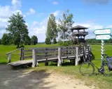 Rower czeka przy drewnianym pomoście, gotowy na odkrywanie tras rowerowych Podlasia. Wieża widokowa zaprasza do podziwiania krajobrazu.