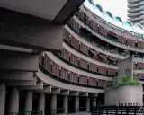 Edifici curvi in cemento con persiane in legno al Barbican Centre. Un'architettura iconica che si staglia nel cielo.